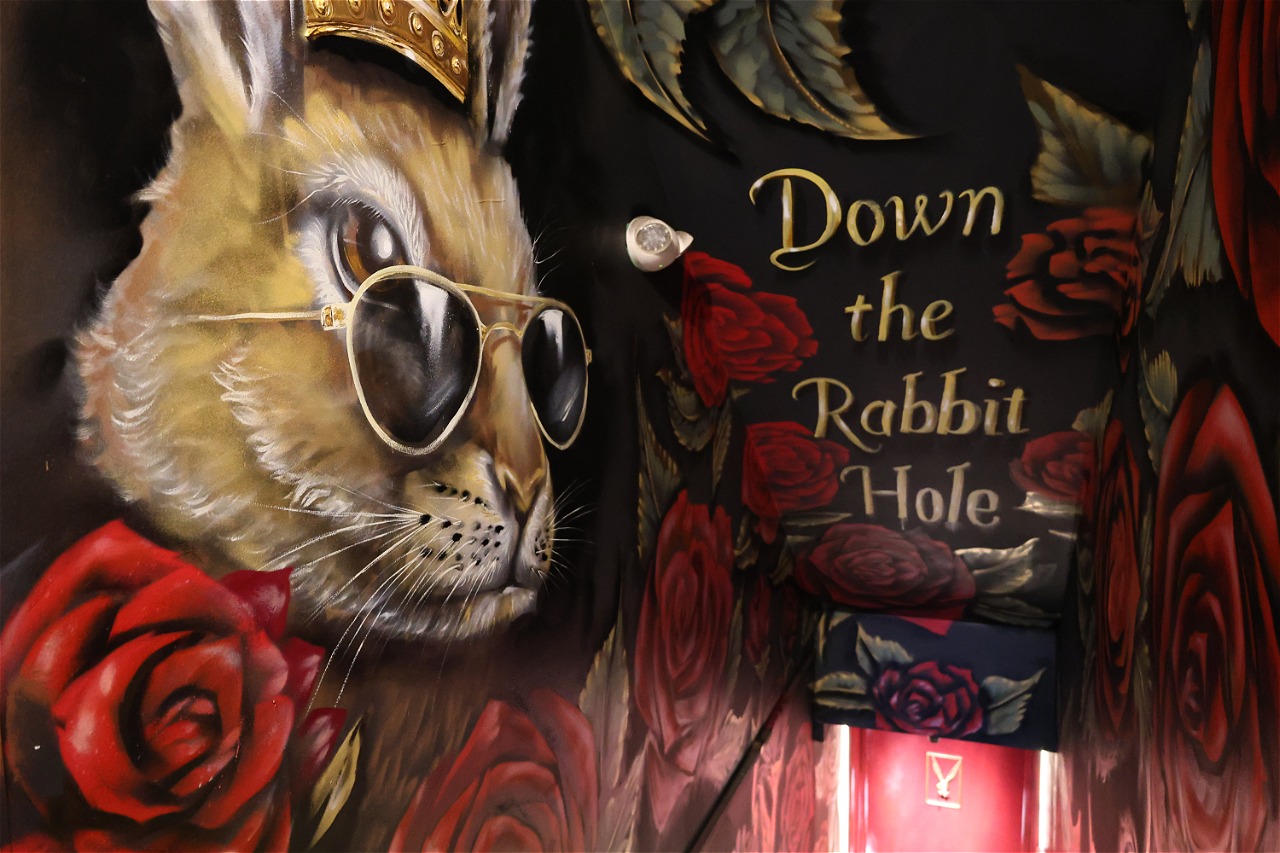 A rose-painted stairway leading down to Bad Rabbit's red door, marked Down the Rabbit Hole.